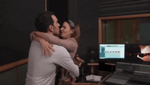 a man and a woman are kissing in front of a computer screen that says ' yamaha ' on it