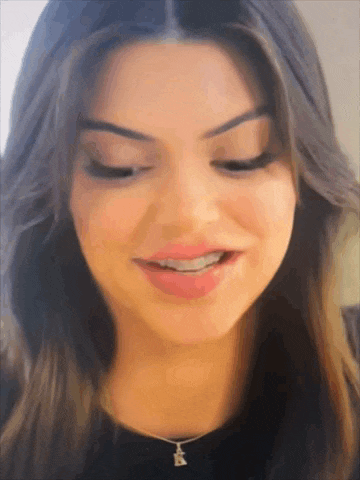 a close up of a woman 's face with a necklace with the letter k on it