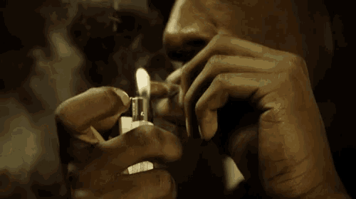 a close up of a person lighting a cigarette with a lighter