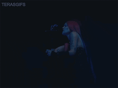 a woman with red hair singing into a microphone with the words terasgifs below her