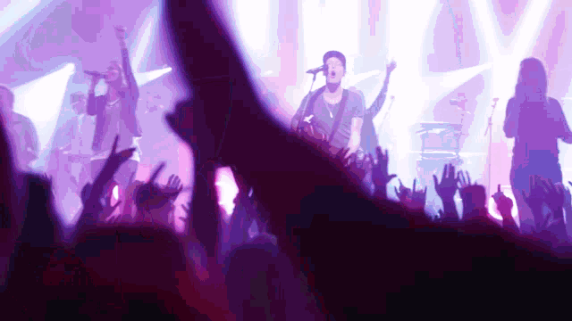 a man singing into a microphone in front of a crowd at a concert