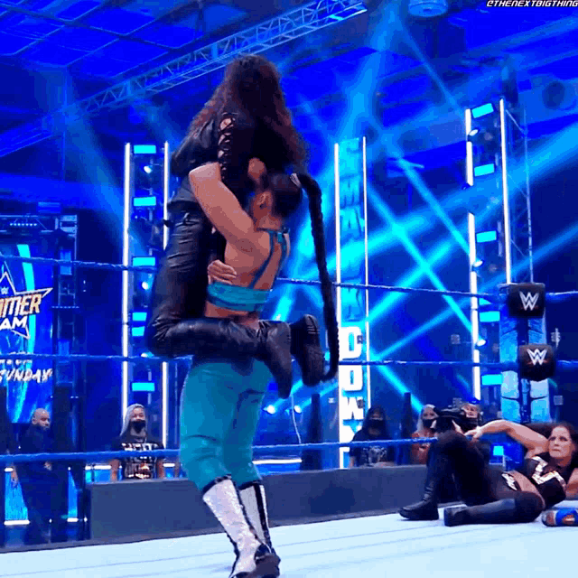 a female wrestler is carrying another wrestler in her arms