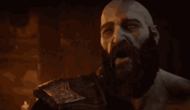 a bald man with a beard is holding his hand to his mouth and looking down .