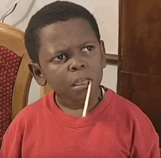 a young boy in a red shirt is holding a toothpick in his mouth .