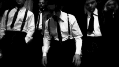a group of men in suits and suspenders are standing next to each other in a black and white photo .