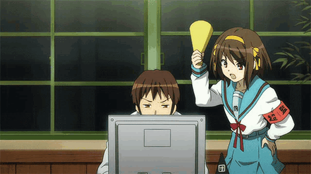 a girl holding a megaphone stands next to a man looking at a computer screen