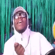 a man wearing a hat and glasses is standing in front of a green background .