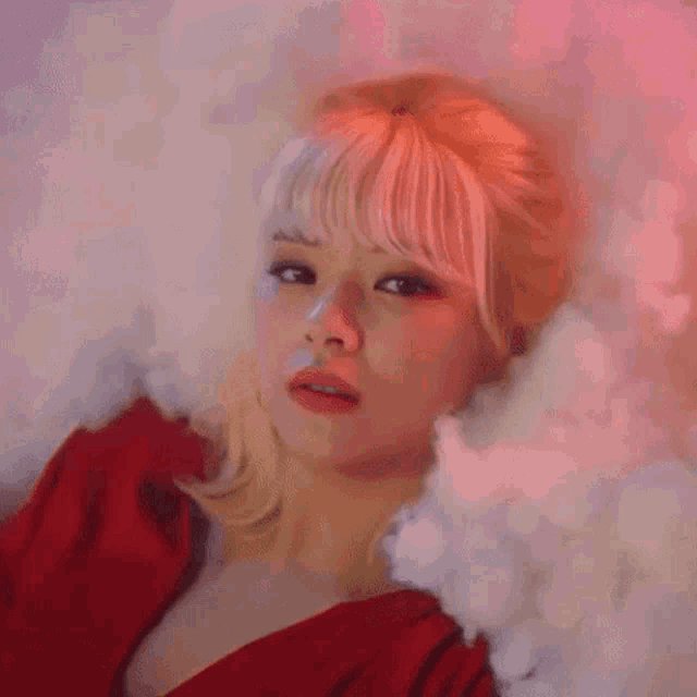 a woman in a red dress is surrounded by smoke and looks at the camera .