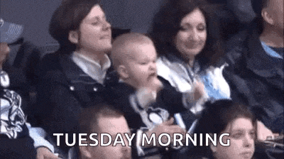 a woman is holding a baby in her arms while sitting in a crowd .