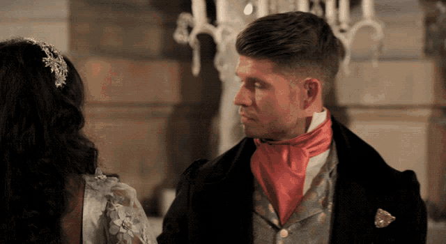 a man with a red scarf around his neck is looking at a woman