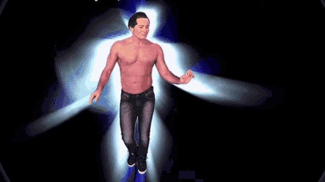 a man without a shirt is dancing in front of a blue light