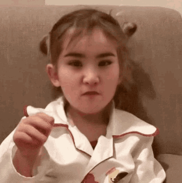 a young girl is sitting on a couch making a funny face .
