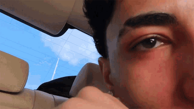 a close up of a man 's eye with a blue sky behind him