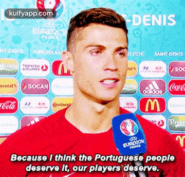 a man in a red shirt is talking into a microphone with the words because i think the portuguese people deserve it