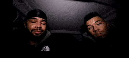 three men are making funny faces in a dark room with a gorilla mask .