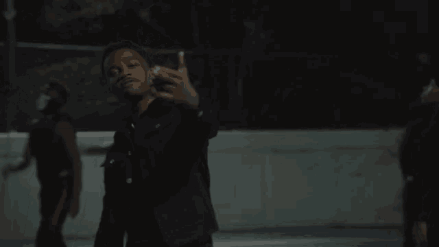 a man in a black jacket is giving the middle finger to the camera