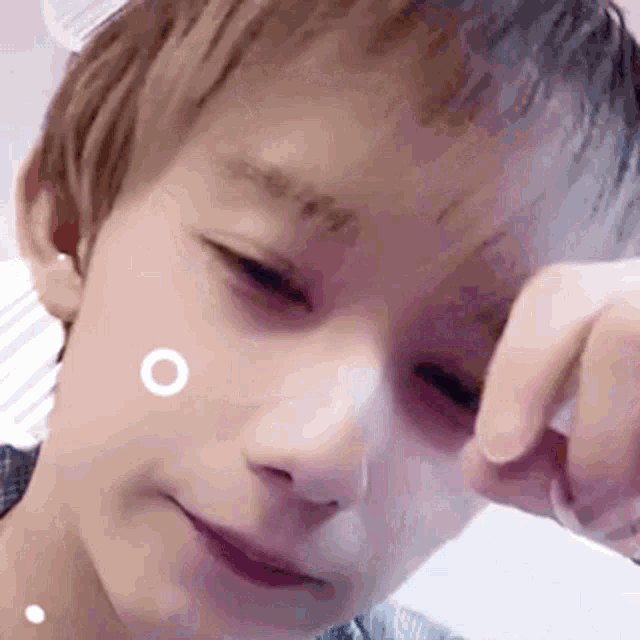 a close up of a young boy 's face with white circles on his face .