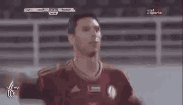 a man in a soccer uniform is standing on a field with his arms outstretched and looking at the camera .