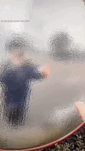 a person is standing in a glass bowl with a reflection of a person in the glass .