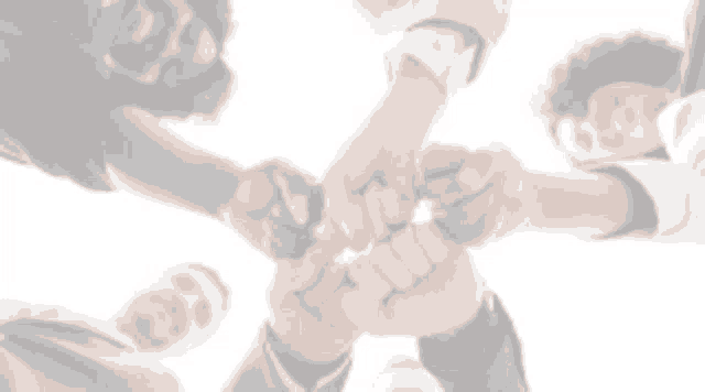 a group of people are putting their hands together .