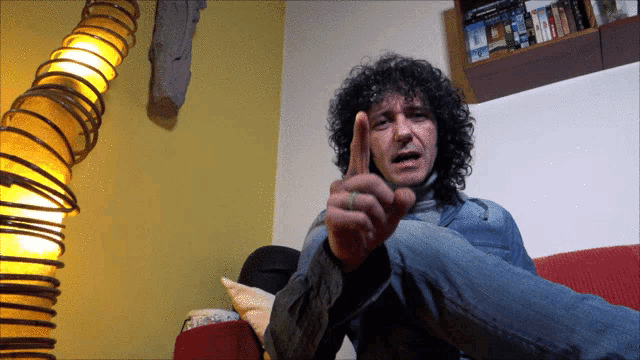 a man with curly hair gives a thumbs up sign