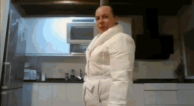 a woman is standing in a kitchen wearing a white coat