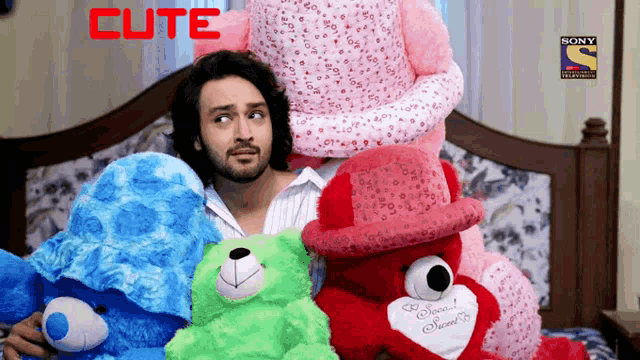 a man sits on a bed surrounded by stuffed animals and the word cute is on the bottom right