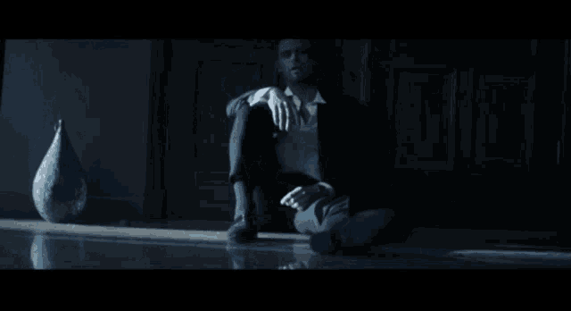 a man in a suit sits on the floor with his feet crossed