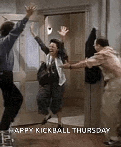 a man and a woman are jumping in the air in a room with the words `` happy kickball thursday '' .