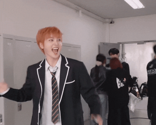 a man in a suit and tie is laughing in a room with lockers