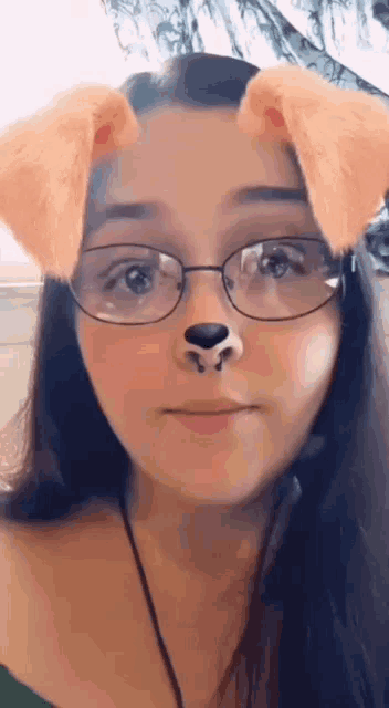 the girl is wearing glasses and has a dog ear filter on her face .