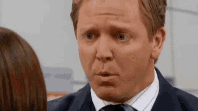 a man in a suit and tie is making a funny face .