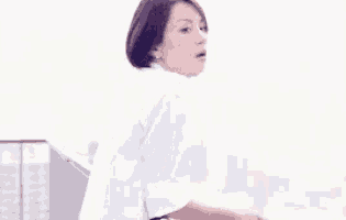 a woman in a white shirt is sitting on a balcony looking out a window .