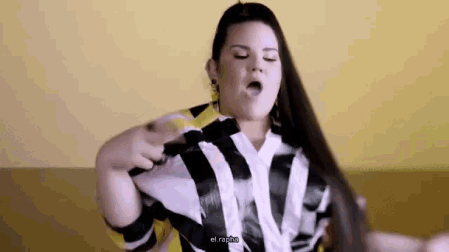 a woman in a black and white striped shirt is holding her hair in her hands .