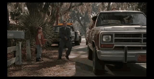 a man in a red shirt stands next to a dodge truck
