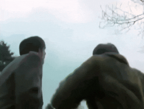 a blurry picture of two people standing next to each other with trees in the background .