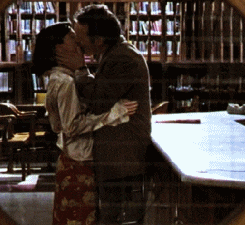 a man and woman kissing in front of a library