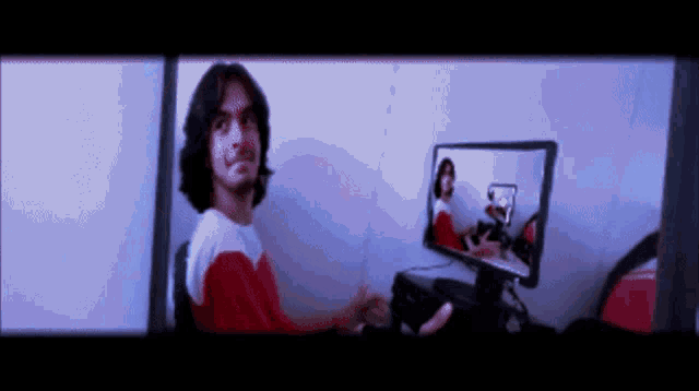 a man sitting in front of a computer monitor with a reflection of a woman on it