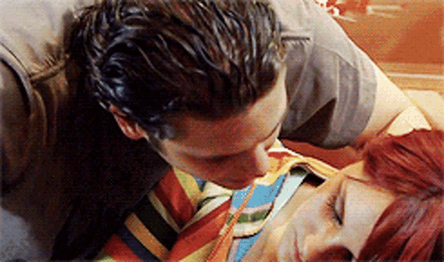 a man kisses a woman on the neck while she sleeps