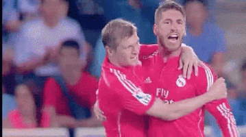 two soccer players are hugging each other and one of them is wearing a fly emirates shirt