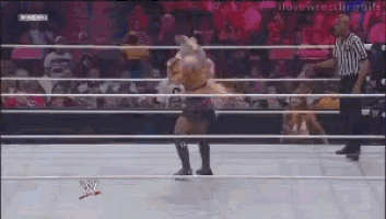 a woman in a wrestling ring with a referee behind her