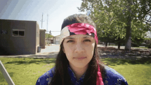 a woman wearing a headband with a flower on it stands in front of a building with the number 26 on it