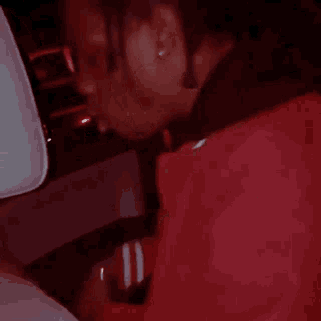 a man in a red jacket is sitting in the back seat of a car and smiling .