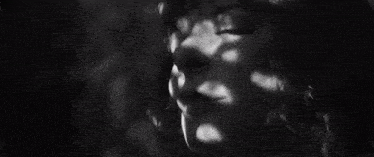 a black and white photo of a woman 's face with a shadow of trees on it .