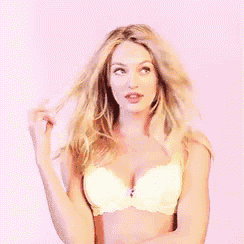 a woman in a white bra is holding her hair .