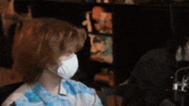 a person wearing a mask is sitting in front of a computer screen .