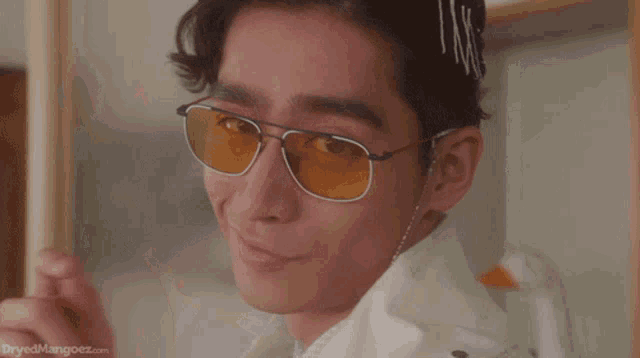 a man wearing glasses and a white jacket has a bunch of hair clips on his head