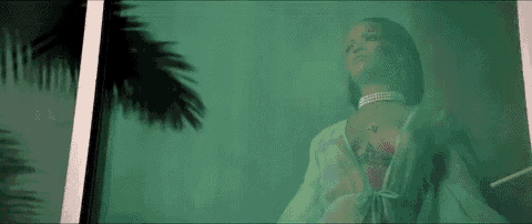 a woman in lingerie is standing in front of a window with a palm tree in the background .