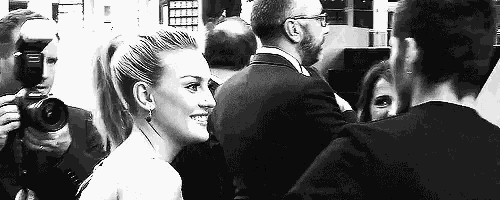 a black and white photo of a man and woman standing next to each other in a crowd .