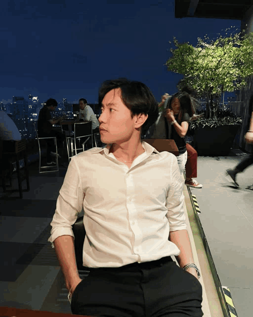 a man in a white shirt sits on a bench